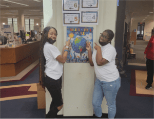 Two people pointing to a poster on the wall