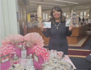 A person holding fashion and beauty products near the table